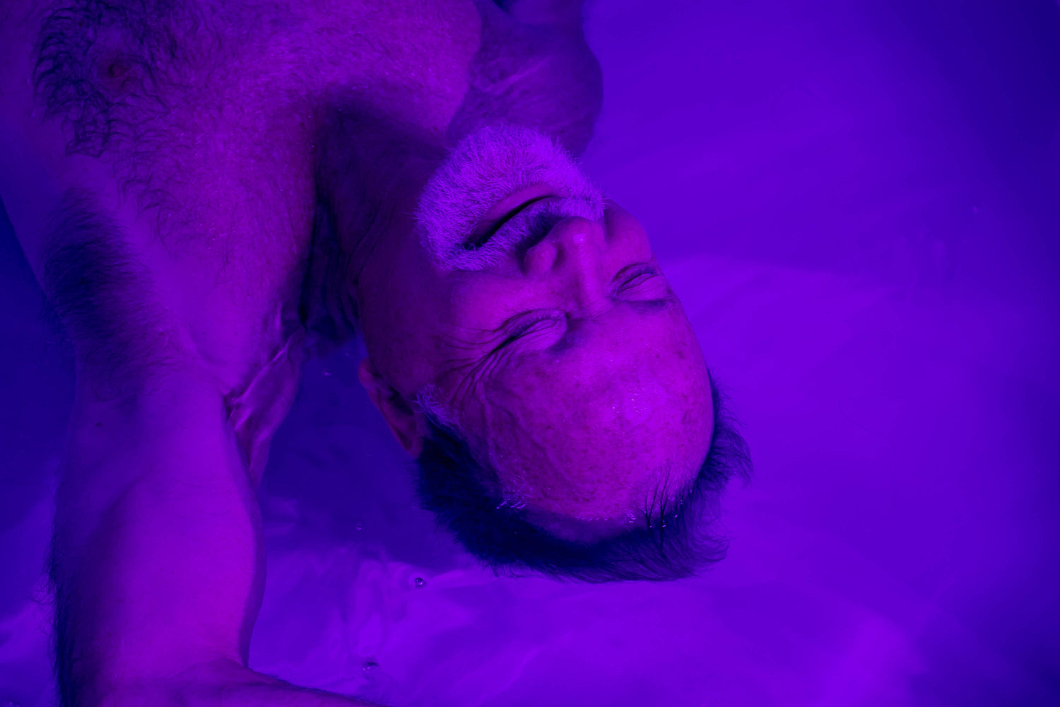 A person floating weightlessly on the surface of the salt water in a Revival float room
